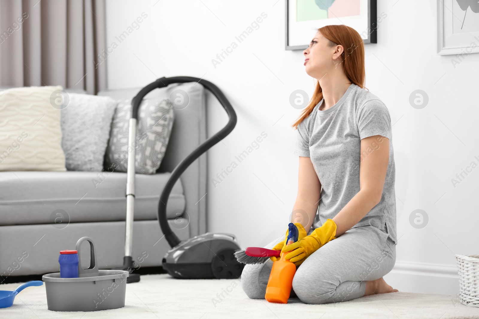 Photo of Tired housewife cleaning carpet at home