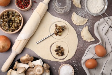 Photo of Process of making dumplings (varenyky) with mushrooms. Raw dough and ingredients on grey table, flat lay