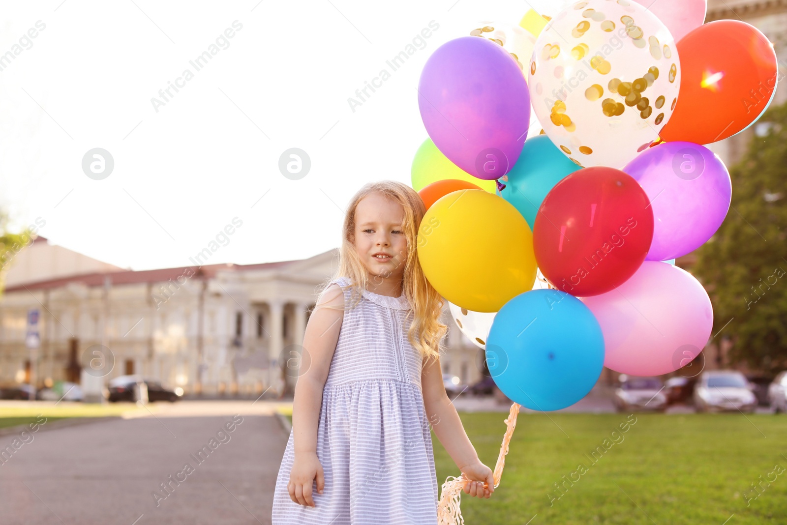 Photo of Cute little girl with colorful balloons outdoors on sunny day