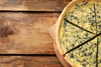 Photo of Cut delicious spinach pie on wooden table, top view. Space for text