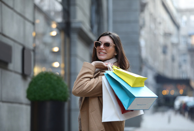 Photo of Beautiful young woman with shopping bags on city street