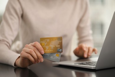 Photo of Woman with credit cards using laptop for online shopping at table, closeup