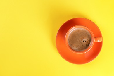 Photo of Coffee in cup on yellow background, top view. Space for text