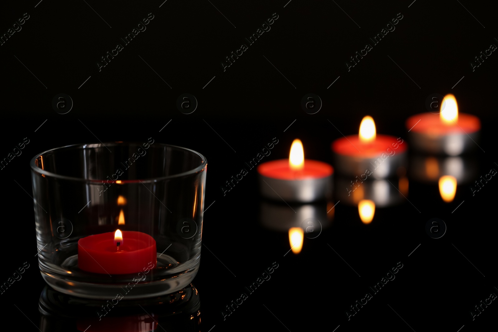 Photo of Wax candles burning on table in darkness. Space for text