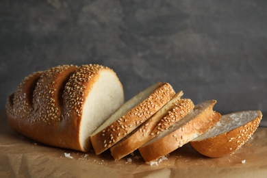 Photo of Tasty wheat bread on parchment paper against grey background