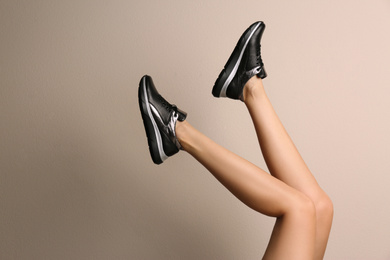 Woman wearing shoes on beige background, closeup