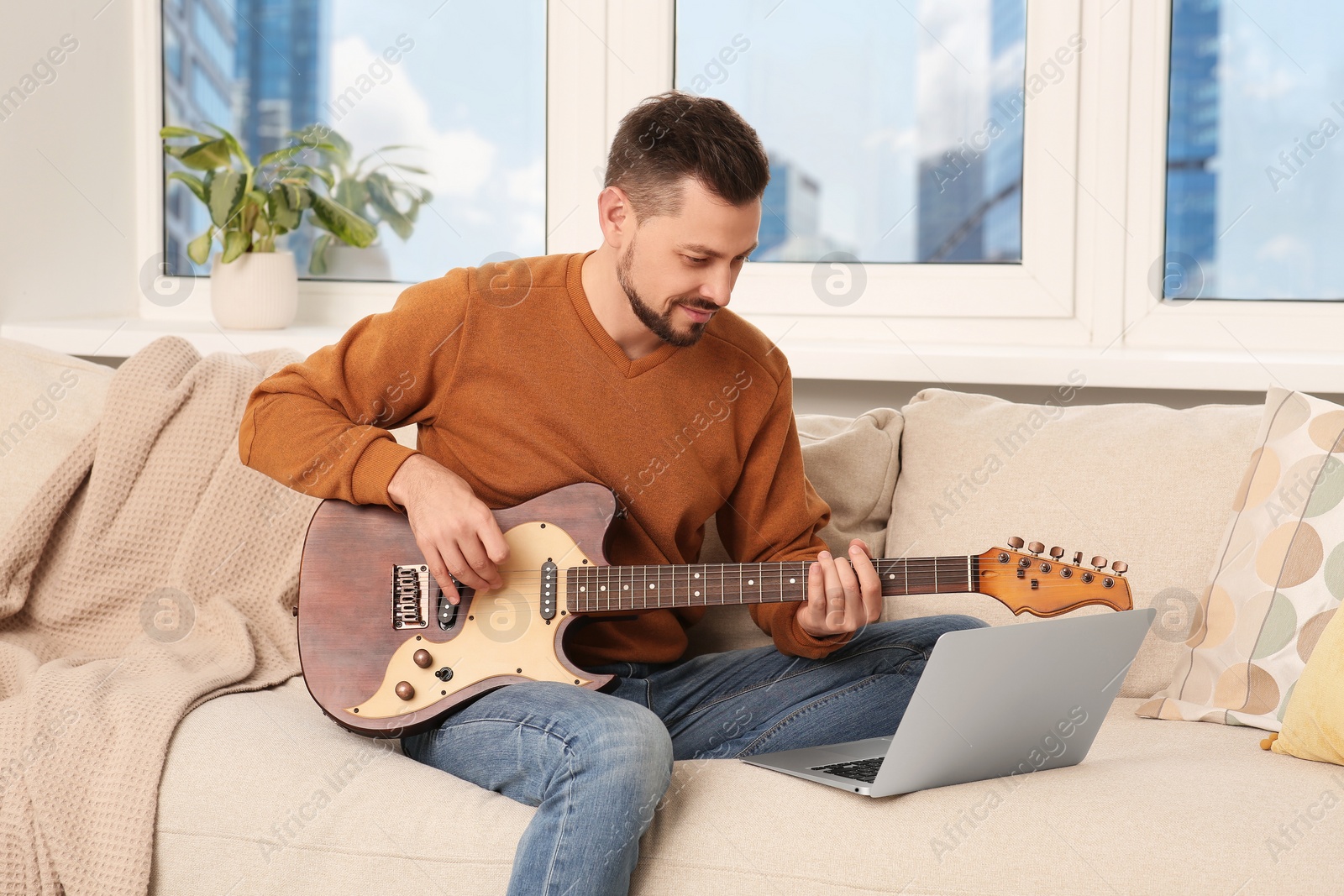 Photo of Man learning to play guitar with online music course at home. Time for hobby