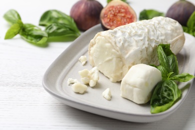 Photo of Delicious goat cheese with basil and figs on white wooden table