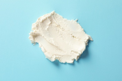 Smear of tasty cream cheese on color background, top view