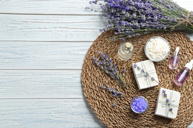 Photo of Flat lay composition of handmade soap bars with lavender flowers on white wooden background. Space for text