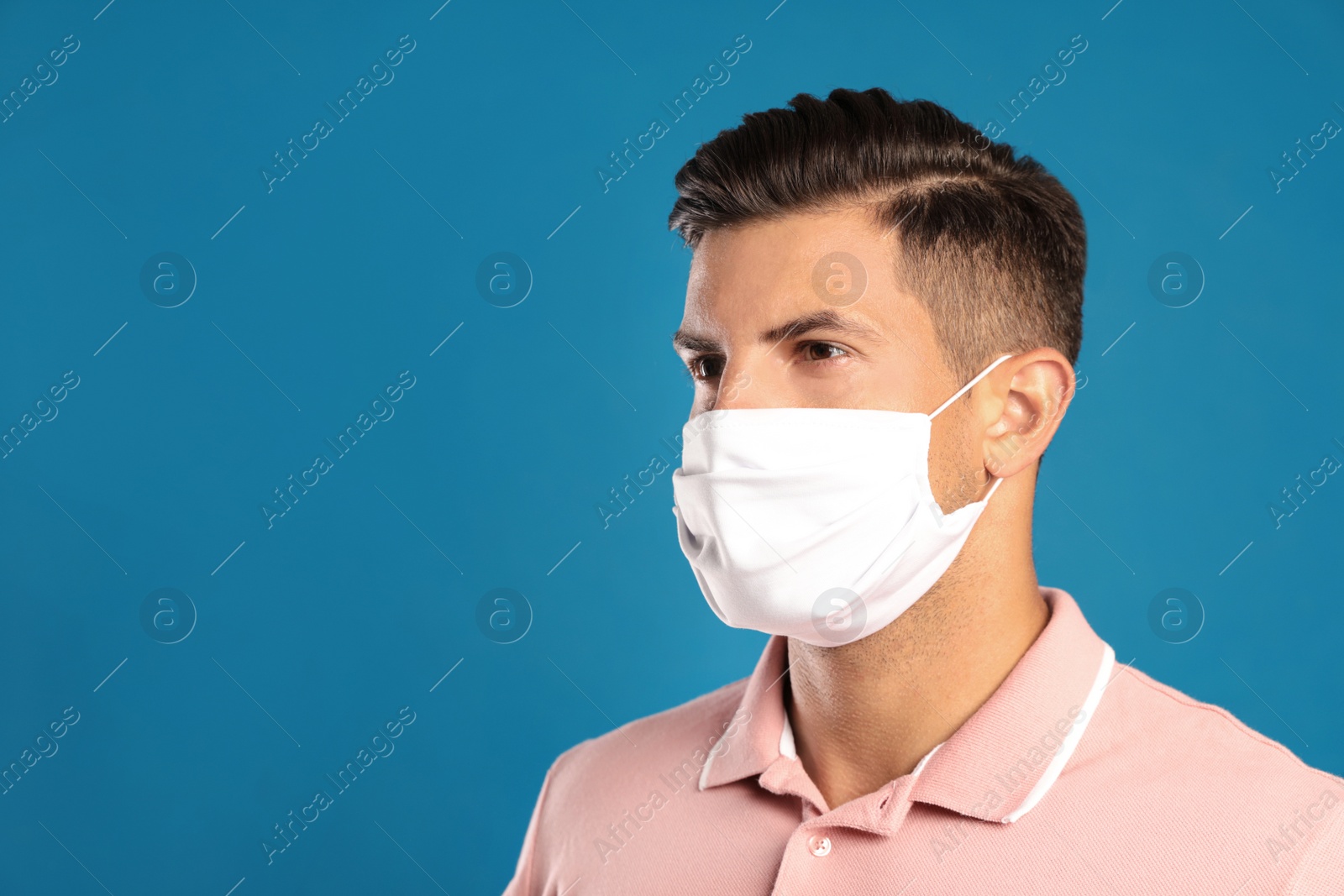 Photo of Man in protective face mask on blue background. Space for text