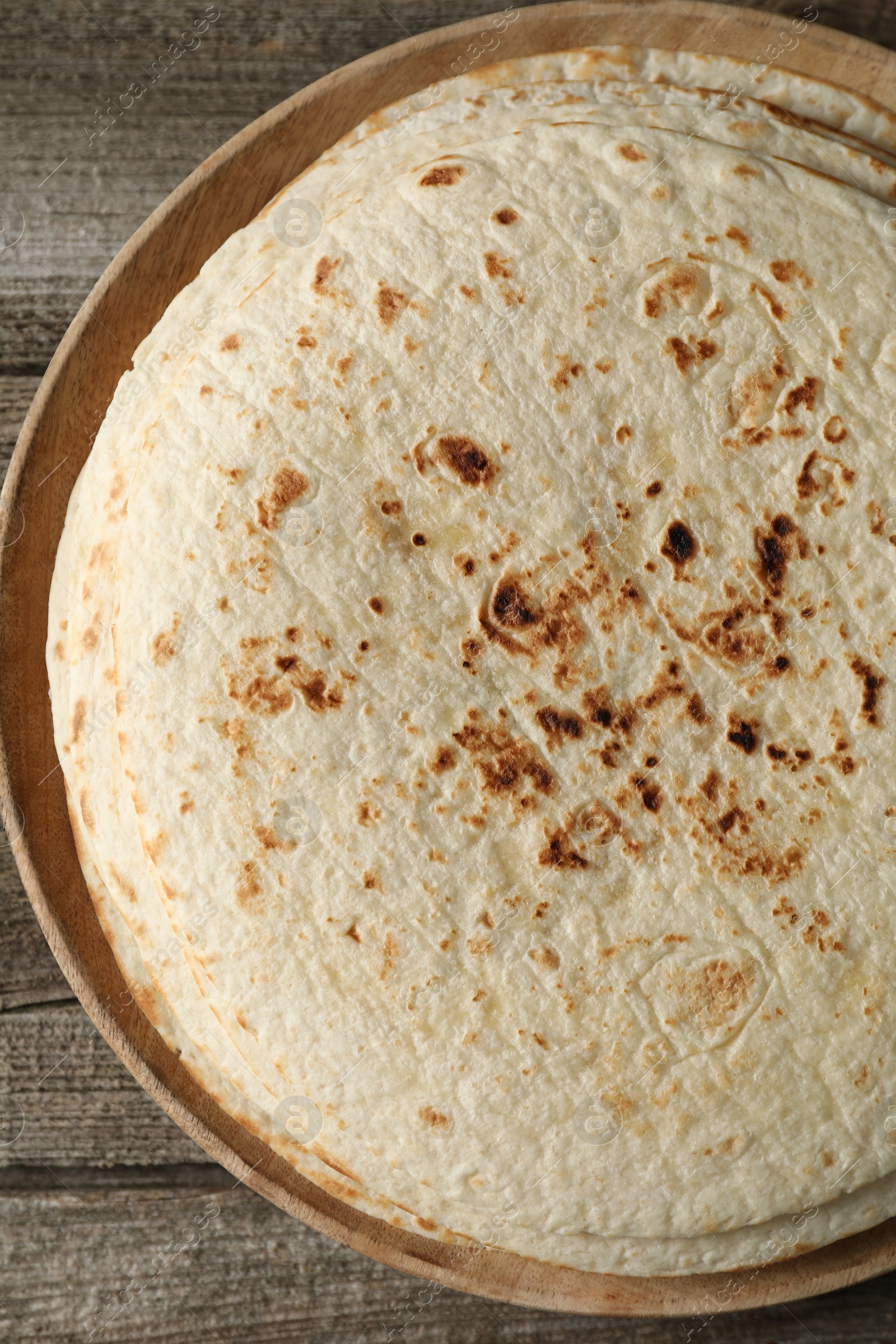 Photo of Stack of tasty homemade tortillas on wooden table, top view