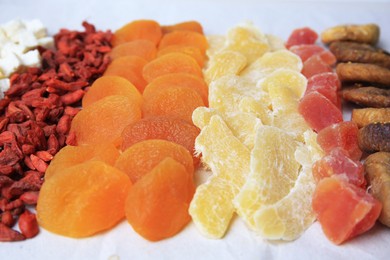 Photo of Different tasty dried fruits on paper, closeup