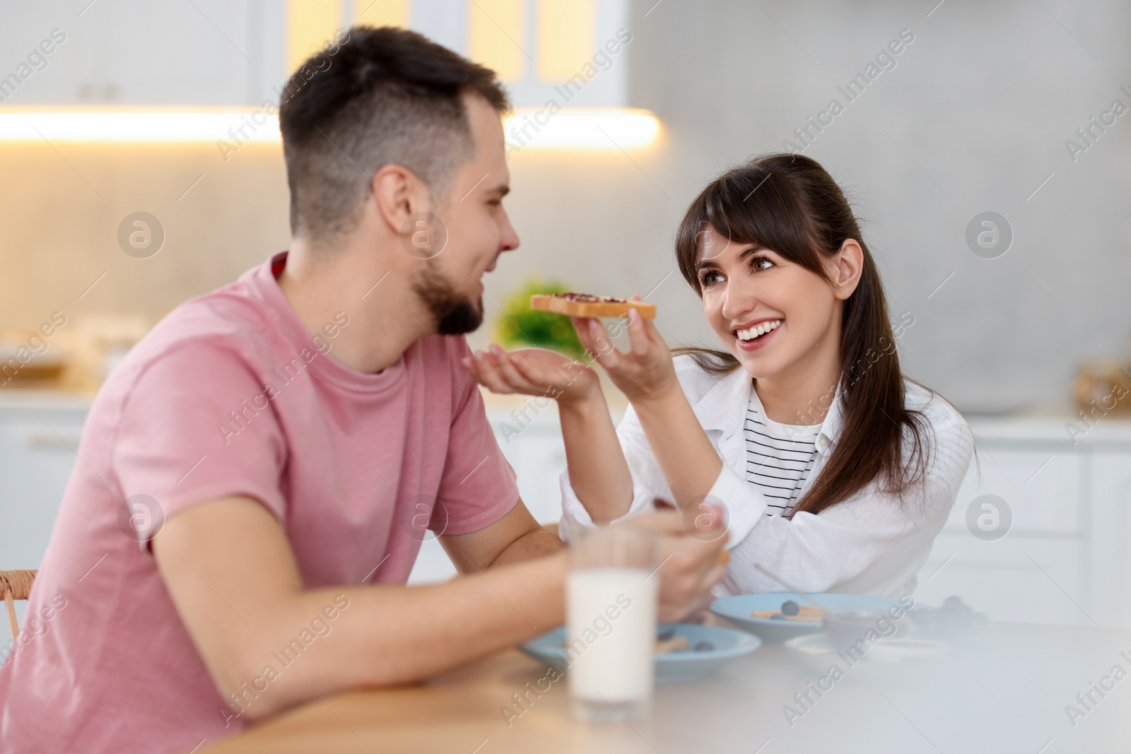 Photo of Tasty breakfast. Happy wife feeding her husband at home