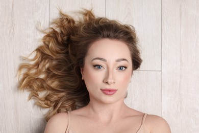 Photo of Portrait of beautiful woman with curly hair on wooden floor, top view