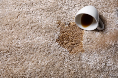 Photo of Overturned cup and spilled coffee on beige carpet, above view. Space for text