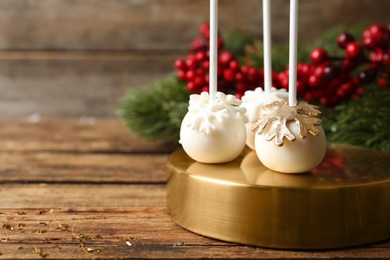Photo of Delicious Christmas ball cake pops on wooden table. Space for text