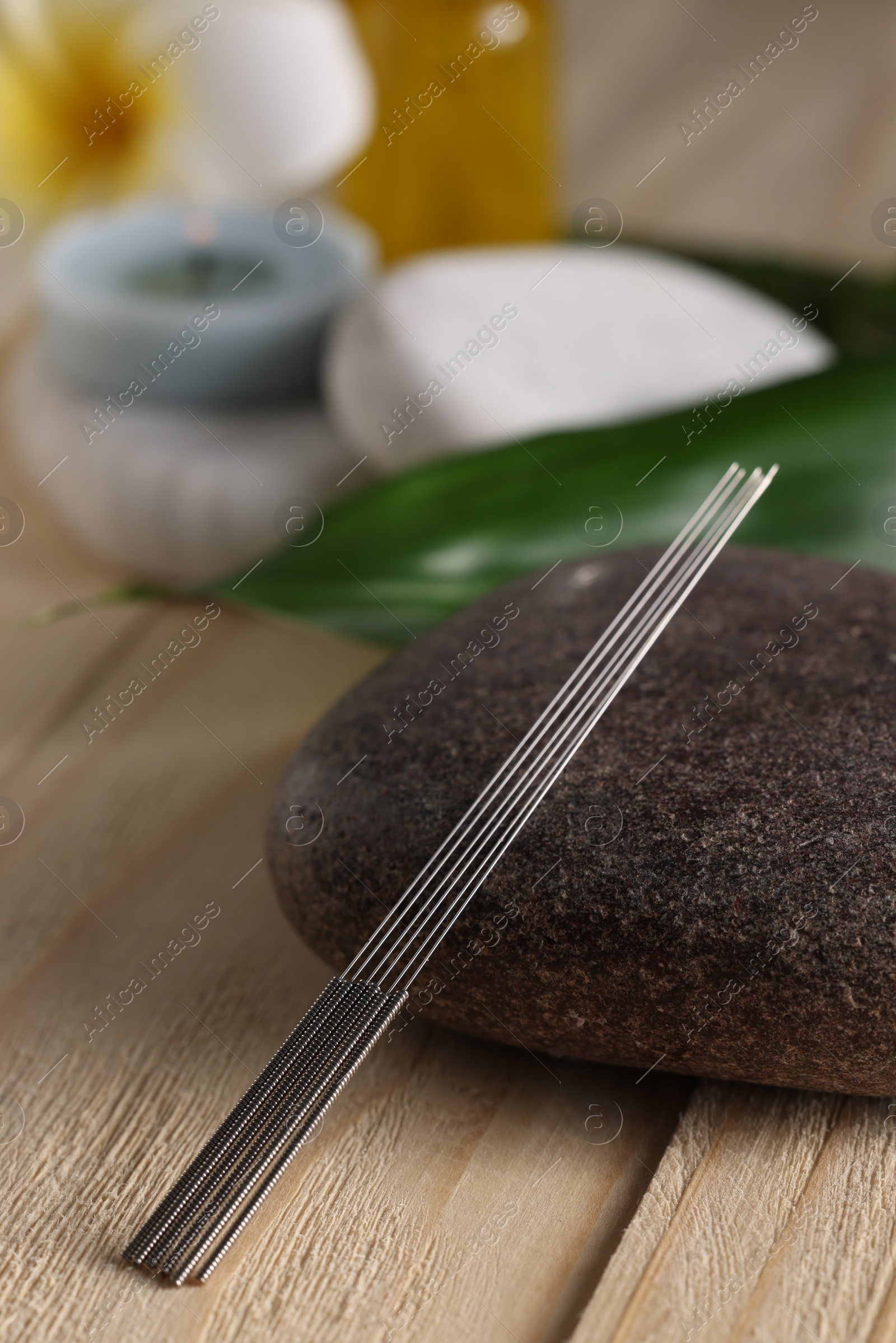 Photo of Acupuncture needles and spa stone on wooden table
