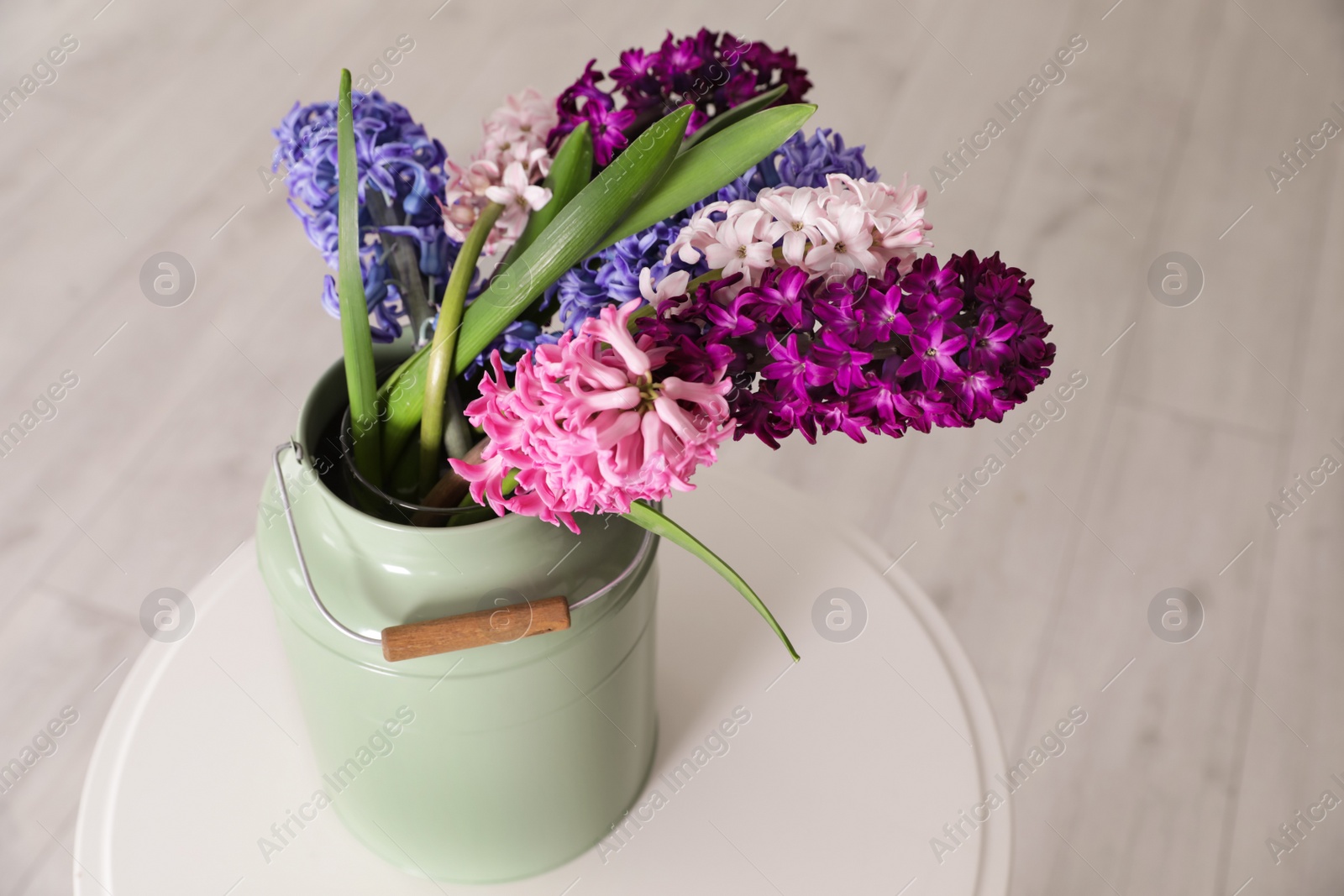 Photo of Beautiful hyacinths in metal can on table, space for text. Spring flowers