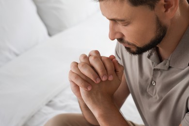 Photo of Religious man praying in bedroom, closeup. Space for text