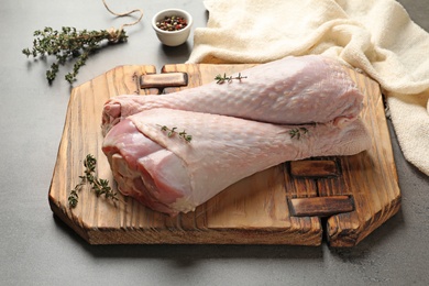 Photo of Board with raw turkey drumsticks, spices and thyme on table