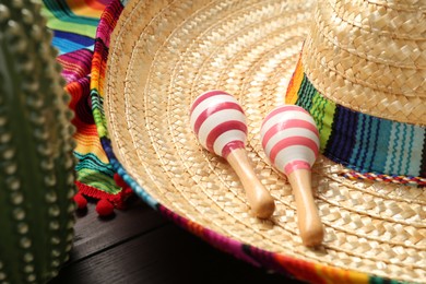 Photo of Mexican sombrero hat, maracas and toy cactus on wooden table