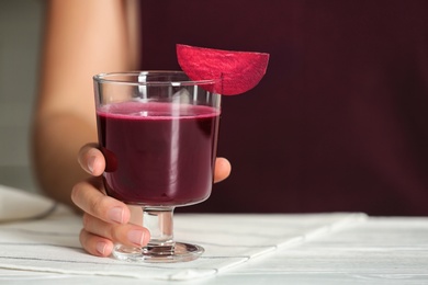 Photo of Woman with glass of beet smoothie at table, closeup