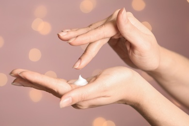 Photo of Woman applying hand cream on blurred background, closeup