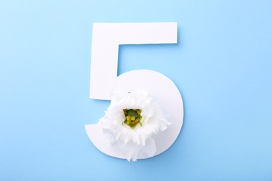 Paper number 5 and beautiful flower on light blue background, top view