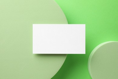 Empty business card and decorative elements on light green background, top view. Mockup for design