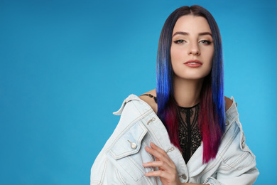 Photo of Young woman with bright dyed hair on blue background, space for text