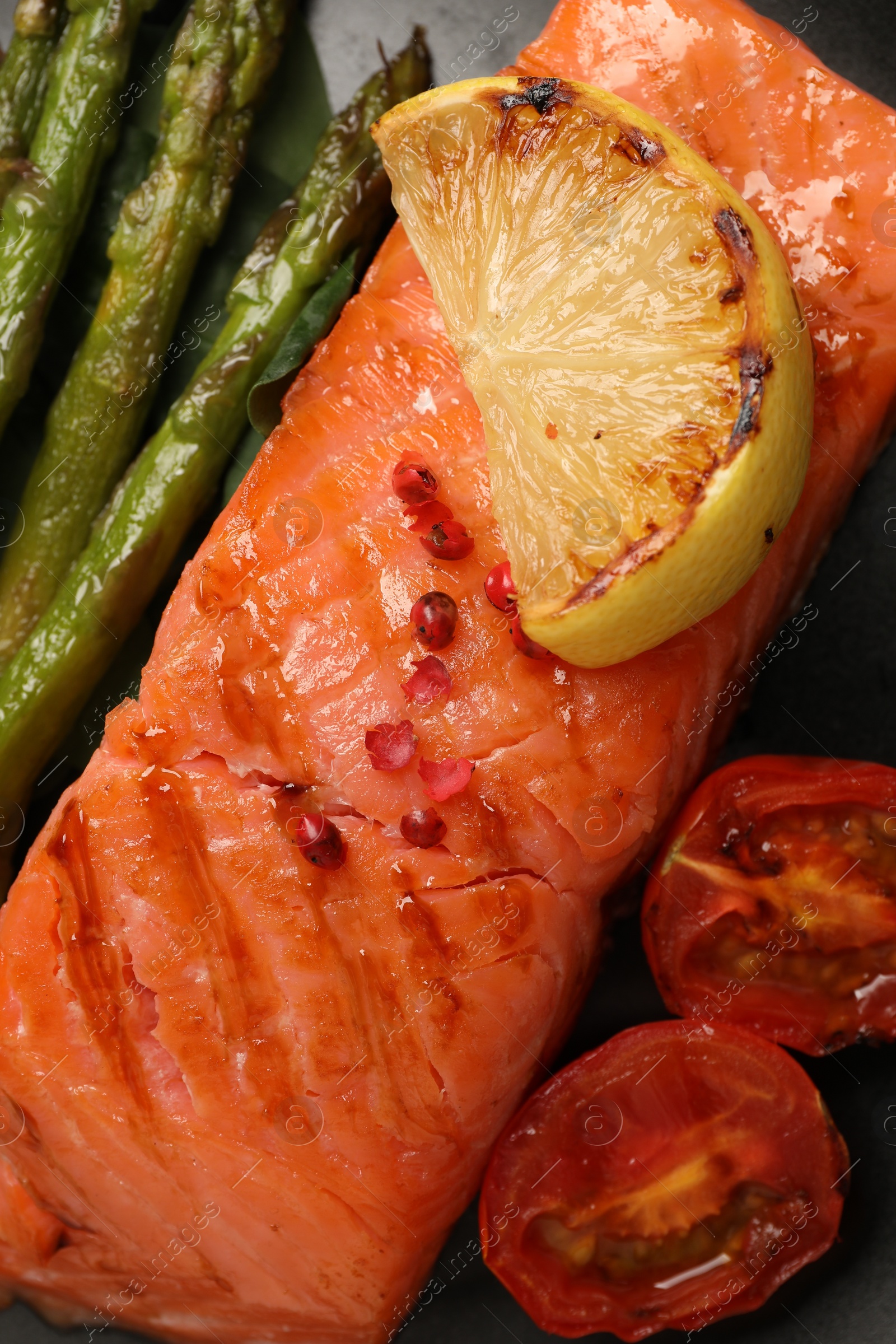 Photo of Plate with tasty grilled salmon, tomatoes, lemon and asparagus, top view