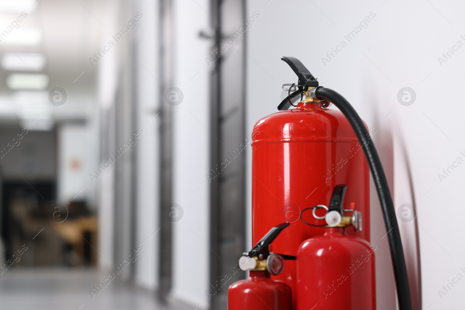 Photo of Fire extinguishers in hall, closeup. Space for text