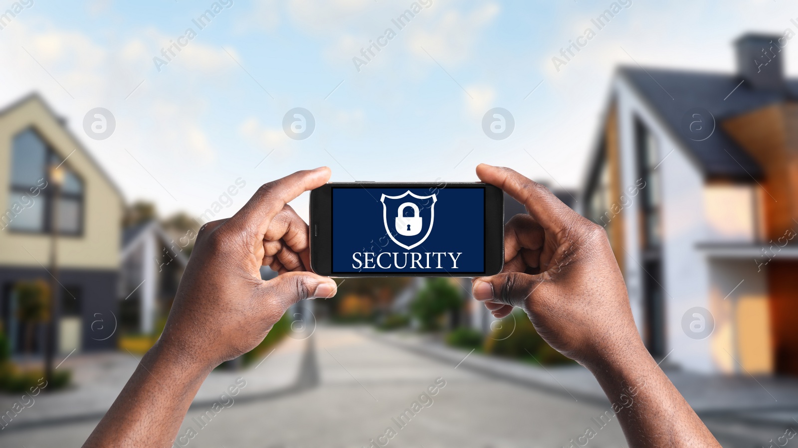 Image of Alarm system. African-American man using phone outdoors, closeup