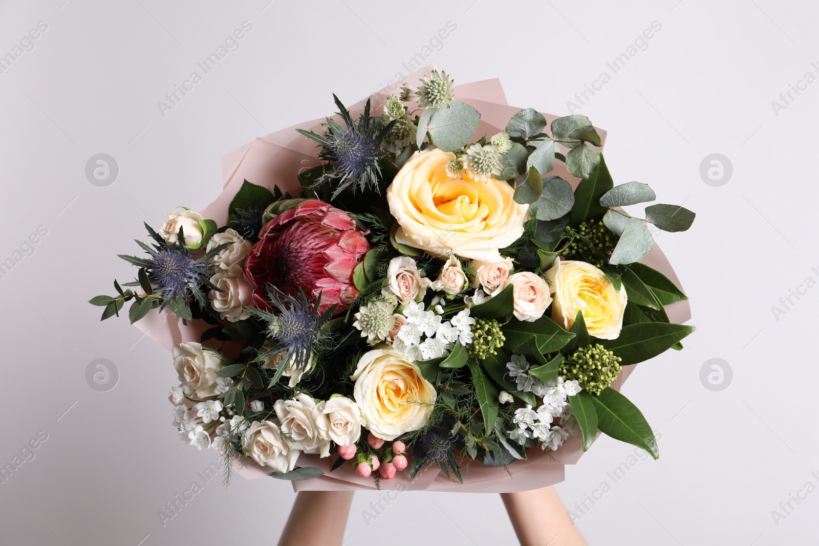 Photo of Woman holding beautiful bouquet with roses on light background, closeup