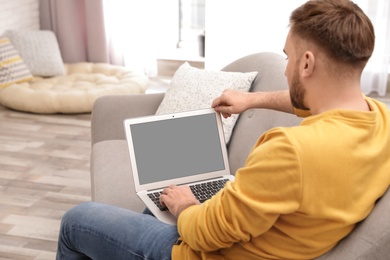 Young man using video chat on laptop in living room. Space for design