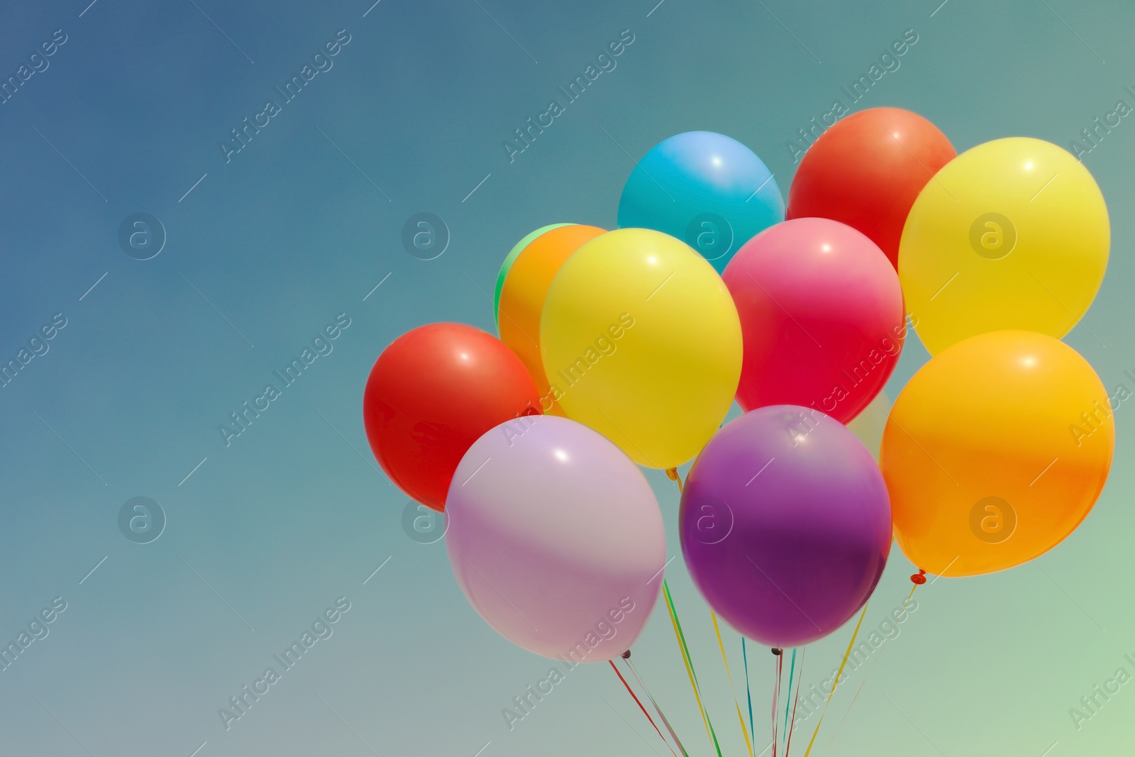 Image of Colorful balloons flying in blue sky on sunny day. Space for text