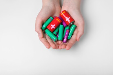 Photo of Woman holding many different batteries on white background, top view