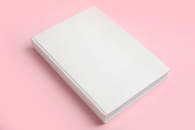 Book with blank cover on pink background