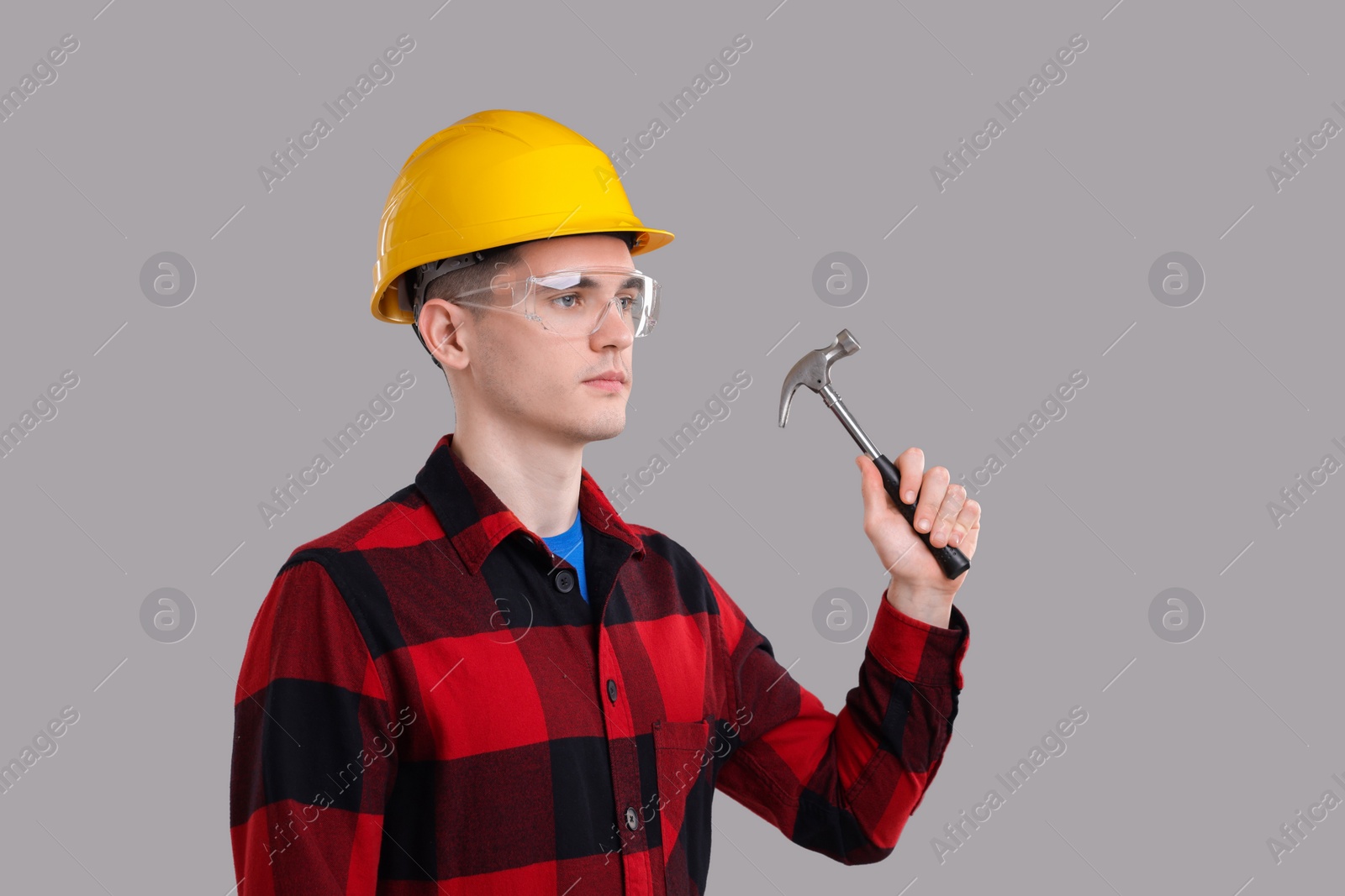 Photo of Professional repairman holding hammer on light grey background