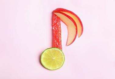 Photo of Musical note made of fruits on color background, top view