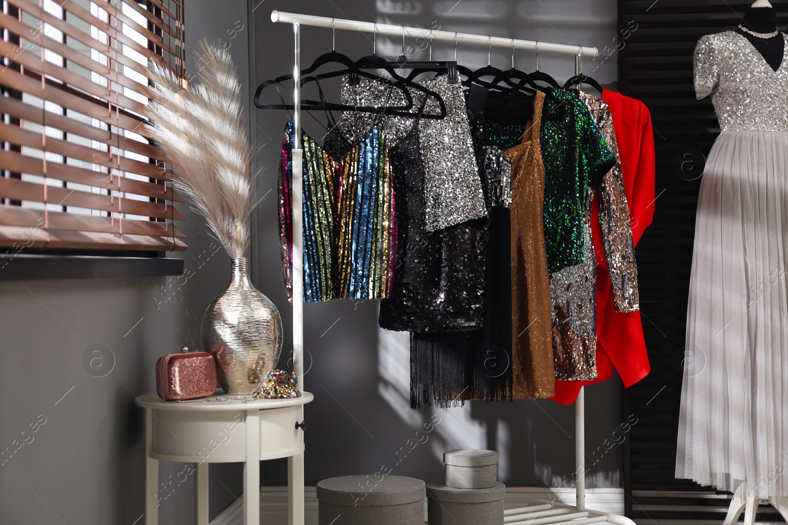 Photo of Rack with collection of beautiful festive clothes in stylish room interior