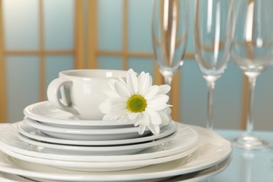 Photo of Set of clean dishware and flower on light blue table, closeup