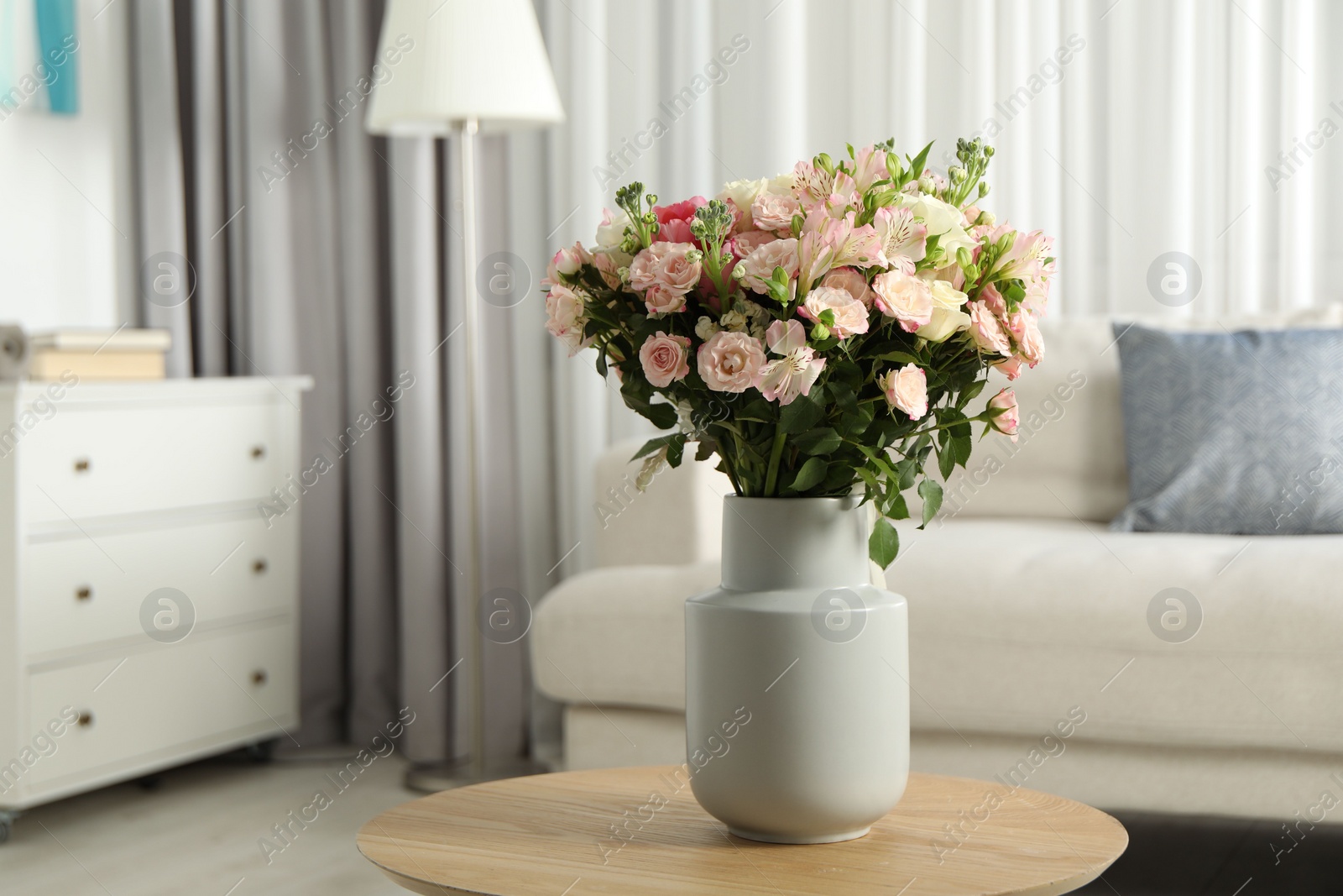 Photo of Beautiful bouquet of fresh flowers in vase on wooden coffee table indoors, space for text