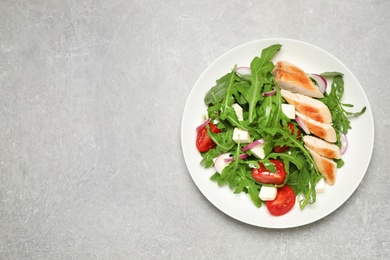 Photo of Delicious salad with meat, arugula and vegetables on grey table, top view. Space for text