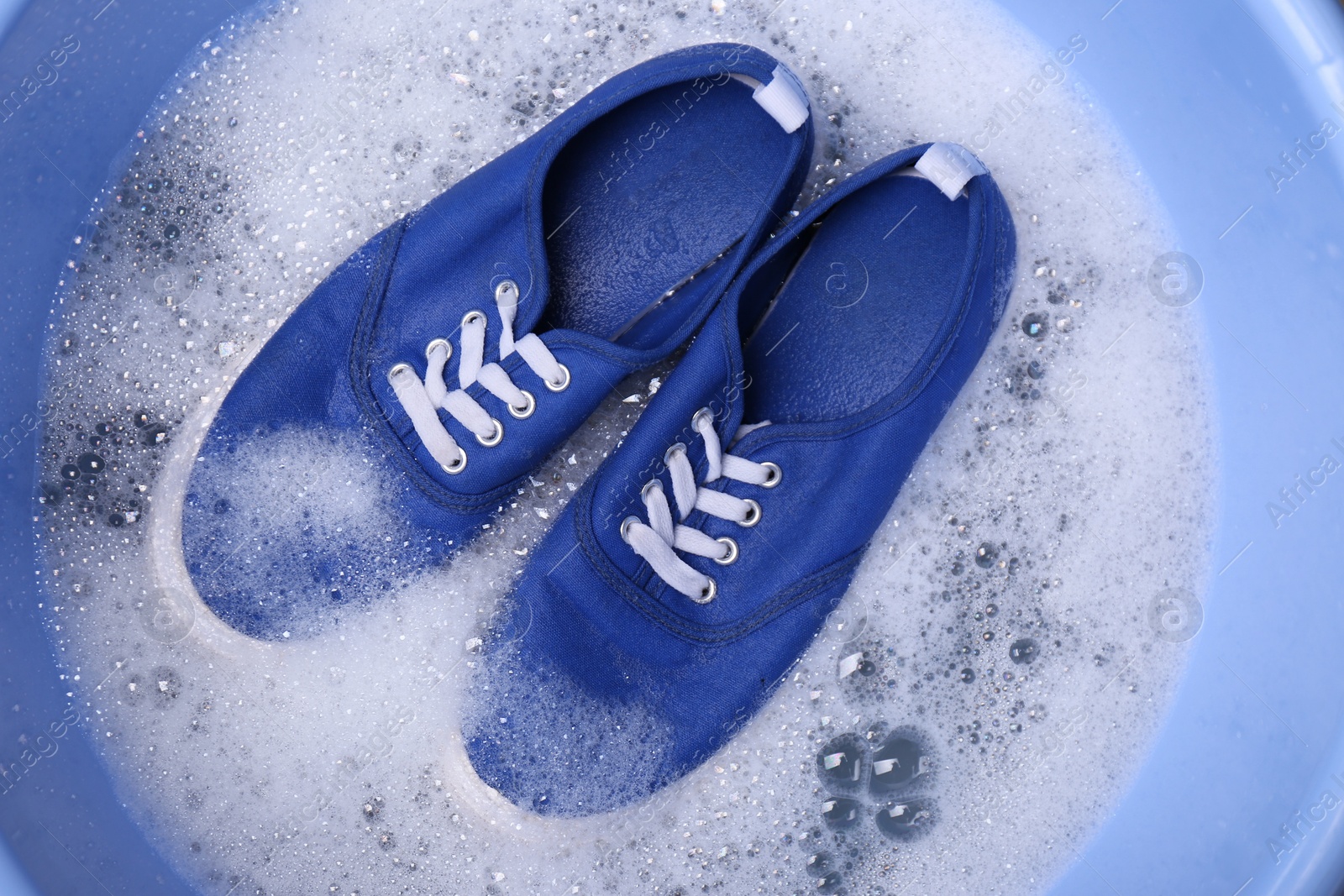 Photo of Washing sport shoes in plastic basin, top view