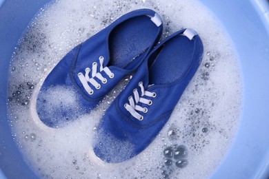 Photo of Washing sport shoes in plastic basin, top view