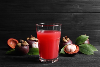 Photo of Delicious fresh mangosteen juice on black wooden table