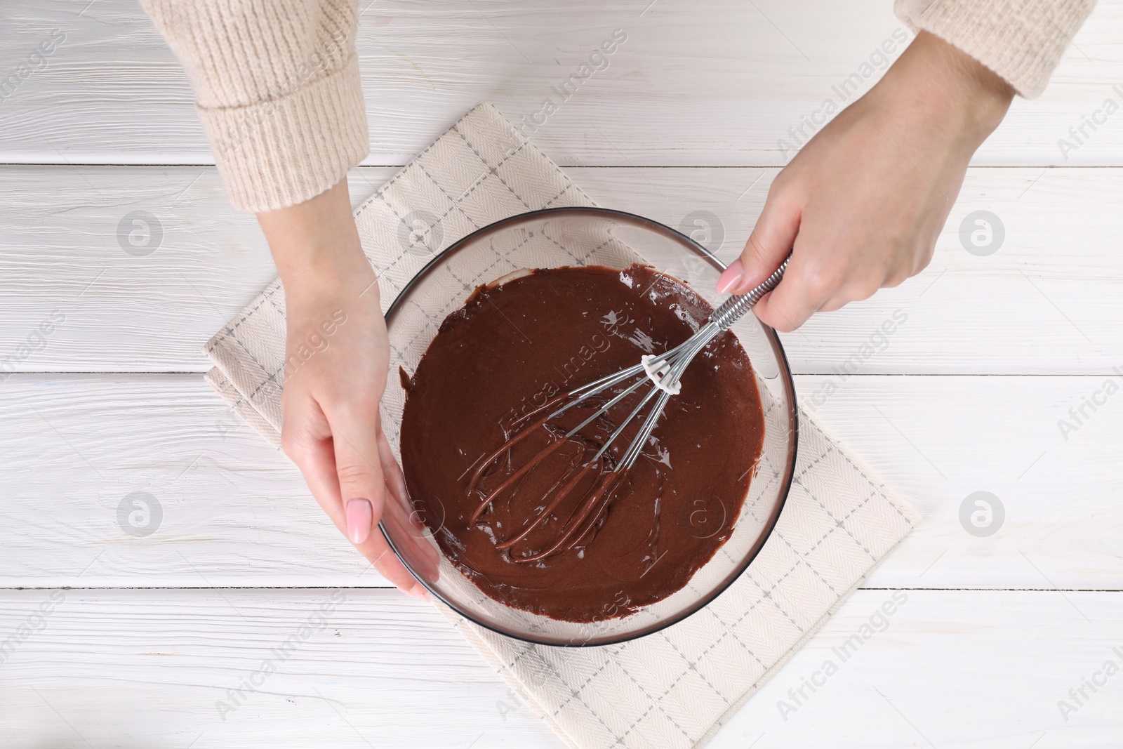 Photo of Woman mixing delicious chocolate cream with whisk at white wooden table, top view