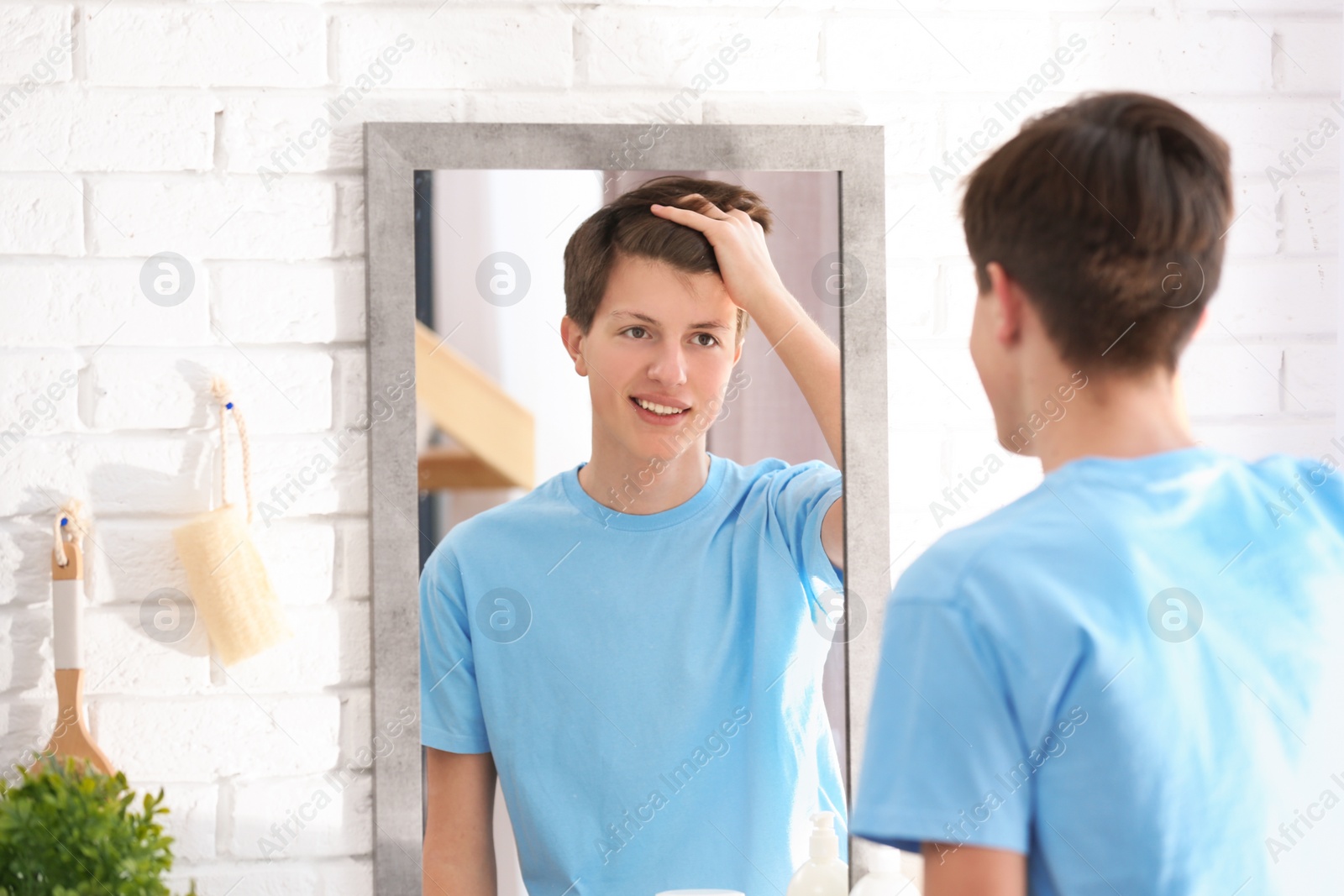 Photo of Teenage boy with acne problem looking in mirror at home